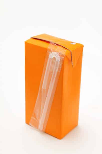 small orange drinks carton with straw - plain background with soft shadows